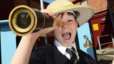 School child dressed up in a hat and using a telescope 